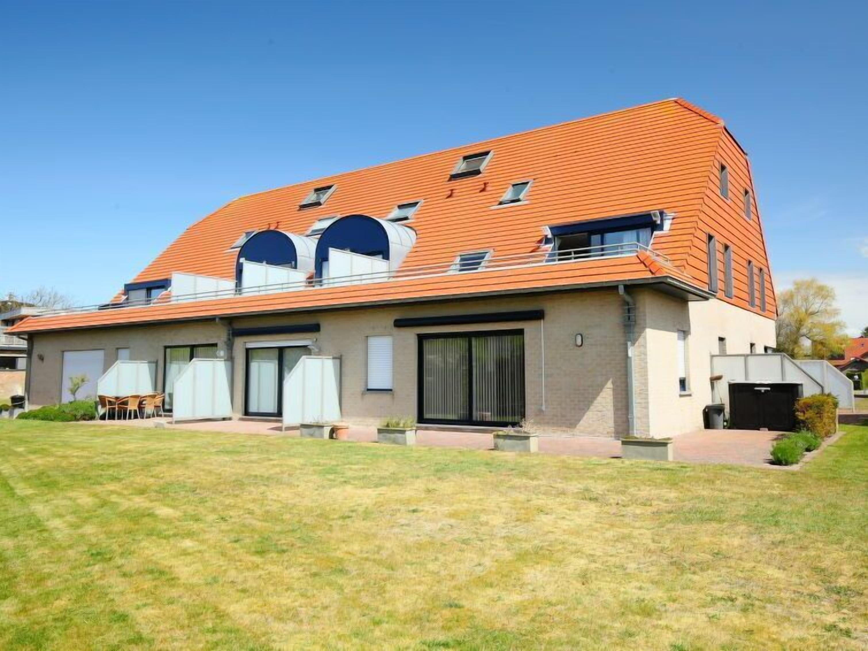 A modern two-story house with a sloped roof, large windows, and a well-maintained lawn.