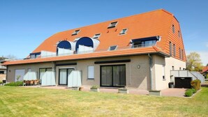 Een modern huis met twee verdiepingen, een schuin dak, grote ramen en een verzorgd gazon.