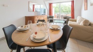 Een eetgedeelte met een ronde tafel voor vier personen, een bank en een televisie op een houten kast.