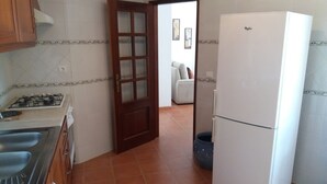 A kitchen with a gas stove, a refrigerator, and a door leading to a living area. - Wonderful villa composed of 3 bedrooms with wardrobes, 2 complete bathrooms. (Foz do Arelho)