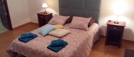 A neatly made bed with a patterned bedspread, two bedside lamps, and a headboard.