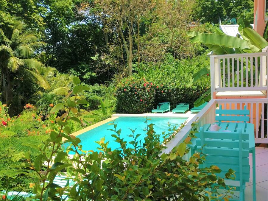 A pool surrounded by lush greenery and a white fence.