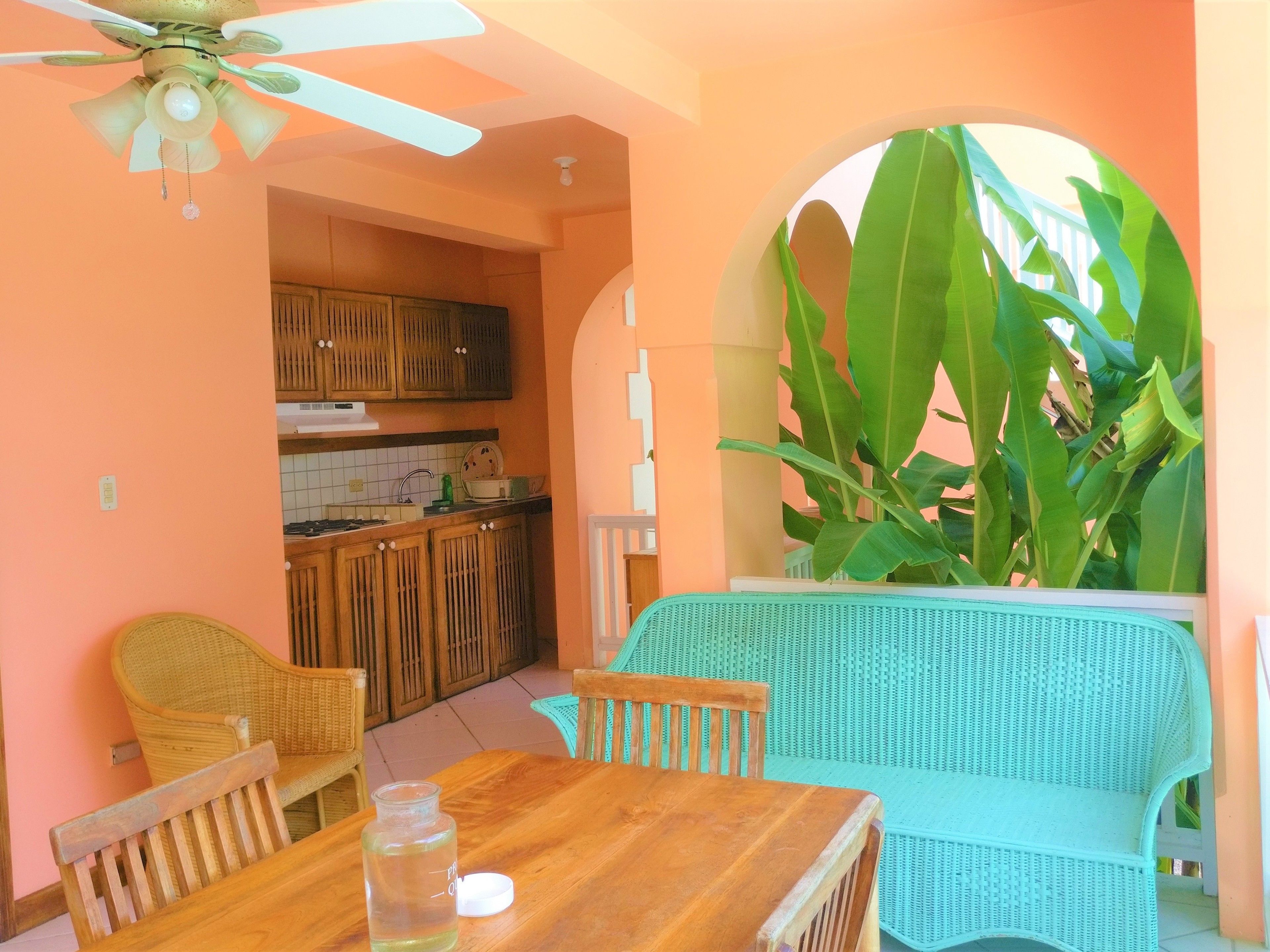 A cozy kitchen with wooden cabinets, a dining table with chairs, and a ceiling fan.