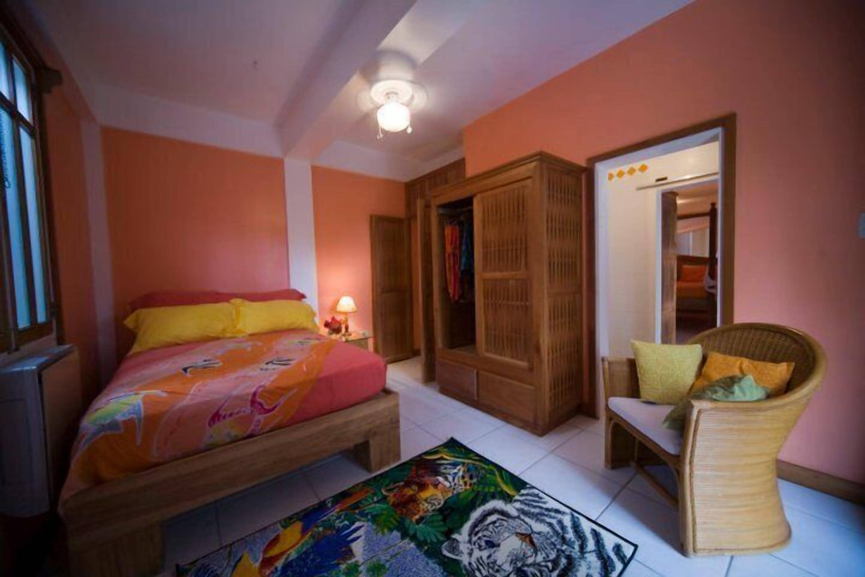 Quarto com uma cama, uma cadeira, um guarda-roupa e uma porta.