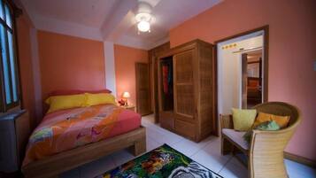 Quarto com uma cama, uma cadeira, um guarda-roupa e uma porta.