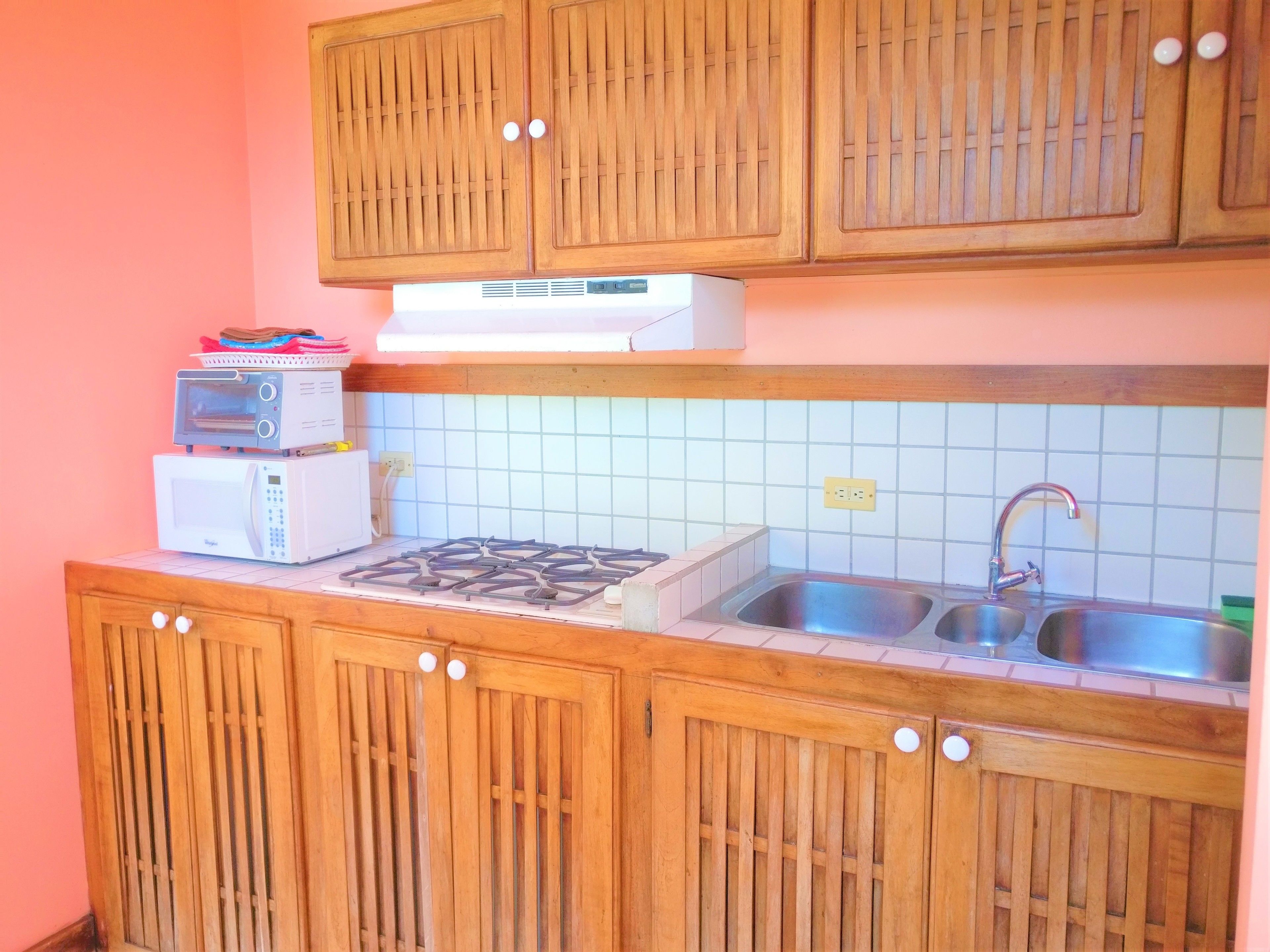 A compact kitchen with wooden cabinets, a gas stove, a microwave, and a sink.