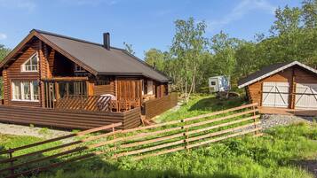 Une cabane en rondins dotée d’une terrasse, d’une petite dépendance attenante et d’un espace clôturé.