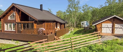 A log cabin with a deck, a small attached structure, and a fenced area.