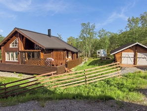 Une cabane en rondins dotée d’une terrasse, d’une petite dépendance attenante et d’un espace clôturé.