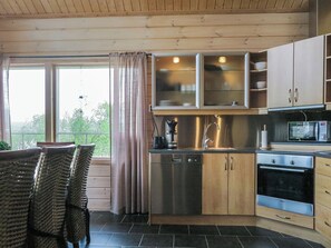 Eine moderne Küche mit Edelstahlgeräten, Holzschränken und einer Essecke mit Korbstühlen.