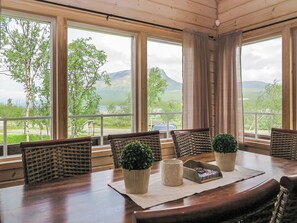 Ein Essbereich mit Blick auf Berge und Bäume durch große Fenster.