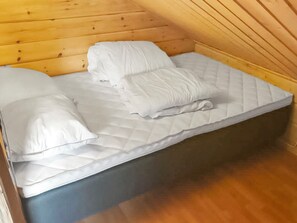 Una cama individual en una habitación de cabaña con techo inclinado.