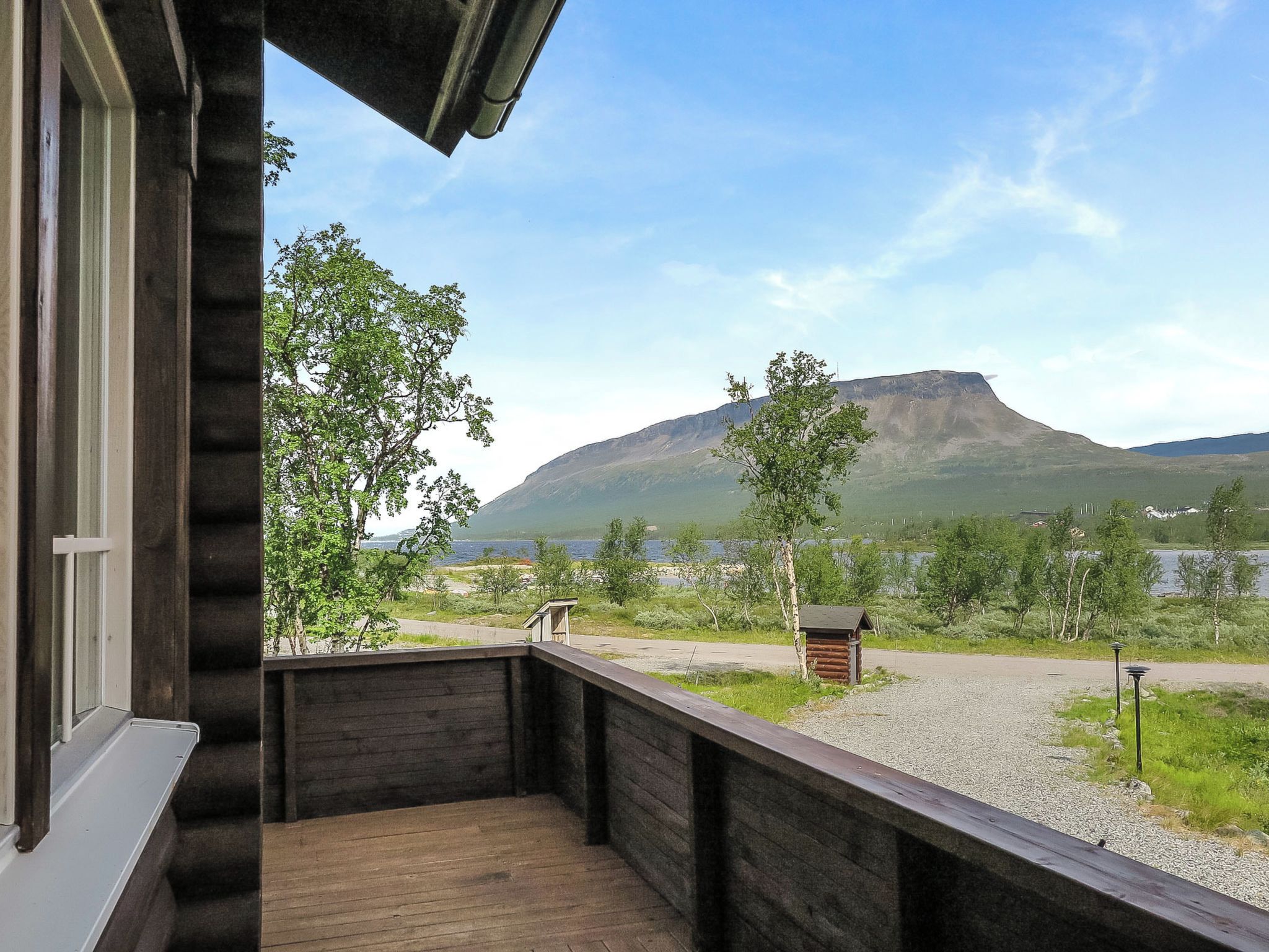A wooden deck with a view of a mountain and a lake.