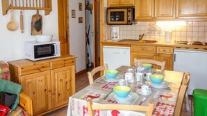 A cozy kitchen with wooden cabinets, a microwave, and a dining table set with bowls and cups.