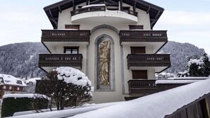 A multi-story building with a central statue, balconies, and a snowy landscape.