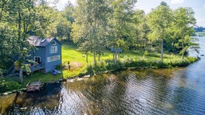 A house by a river with a dock and a small boat.