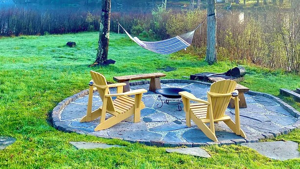 A circular outdoor seating area with wooden chairs and a central table, surrounded by a stone-paved circle.