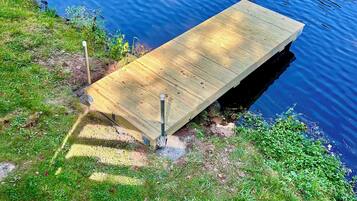 Una banchina di legno si estende in uno specchio d'acqua, circondata da zone erbose.