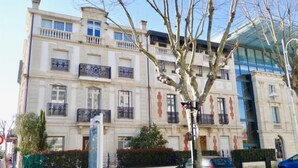 Un immeuble à plusieurs étages doté de balcons, d’une entrée sécurisée et d’une structure moderne en verre attenante.