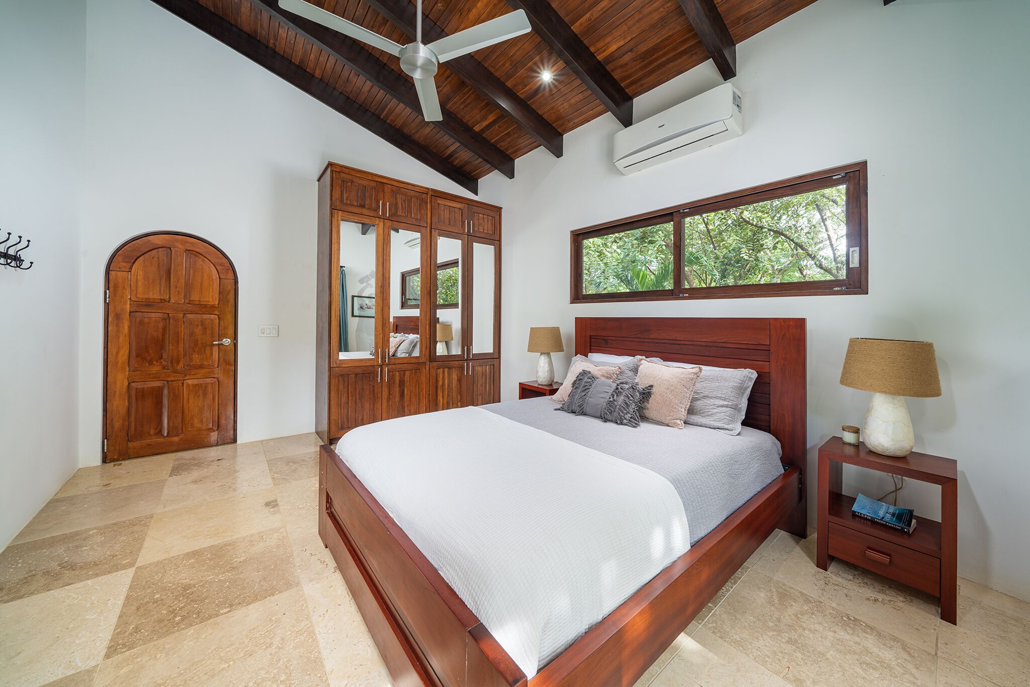 A bedroom with a wooden bed, a nightstand, a wardrobe, and a ceiling fan.