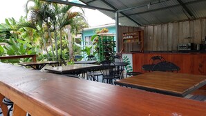 An outdoor seating area with wooden tables and chairs, surrounded by lush greenery and a corrugated metal roof. - Saltish Hotel & Villas (Bahía Ballena)