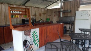 A rustic outdoor kitchen with wooden walls, a wooden counter, and a mural. - Saltish Hotel & Villas (Bahía Ballena)