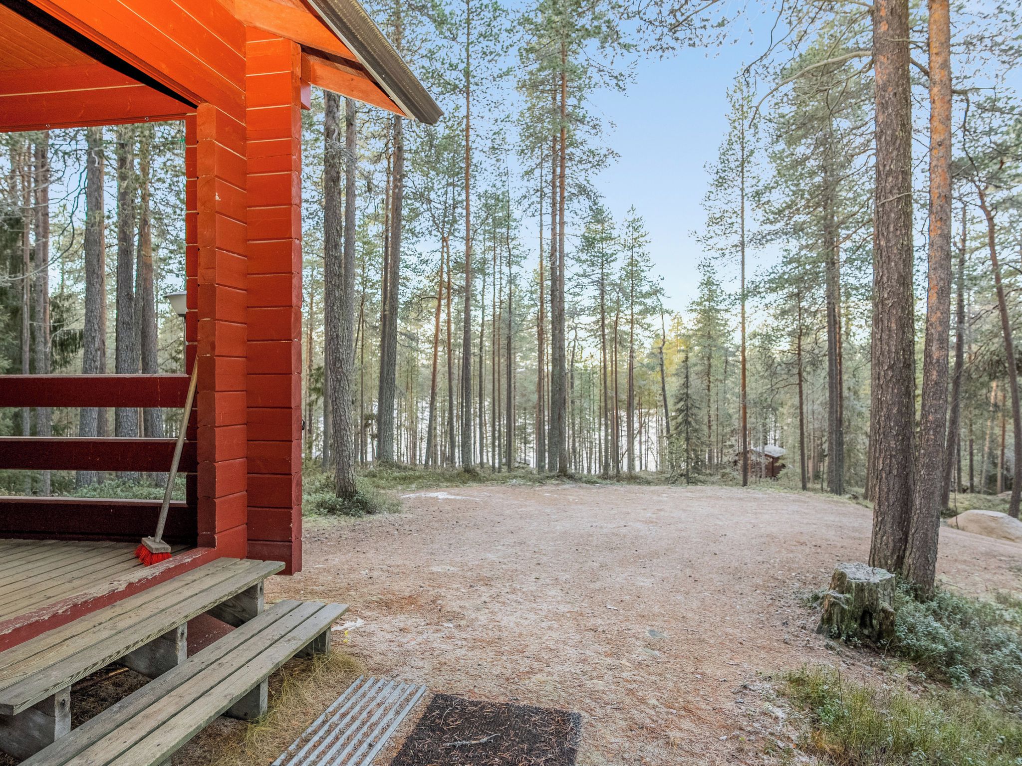 Une cabane en bois avec un banc et une grille en métal devant.