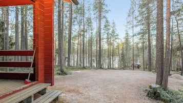 A wooden cabin with a bench and a metal grate in front.