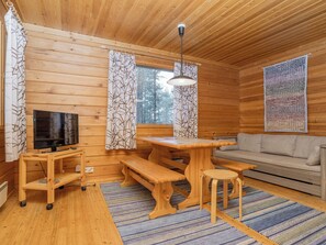A wooden interior with a television, wooden furniture, and a window with curtains.