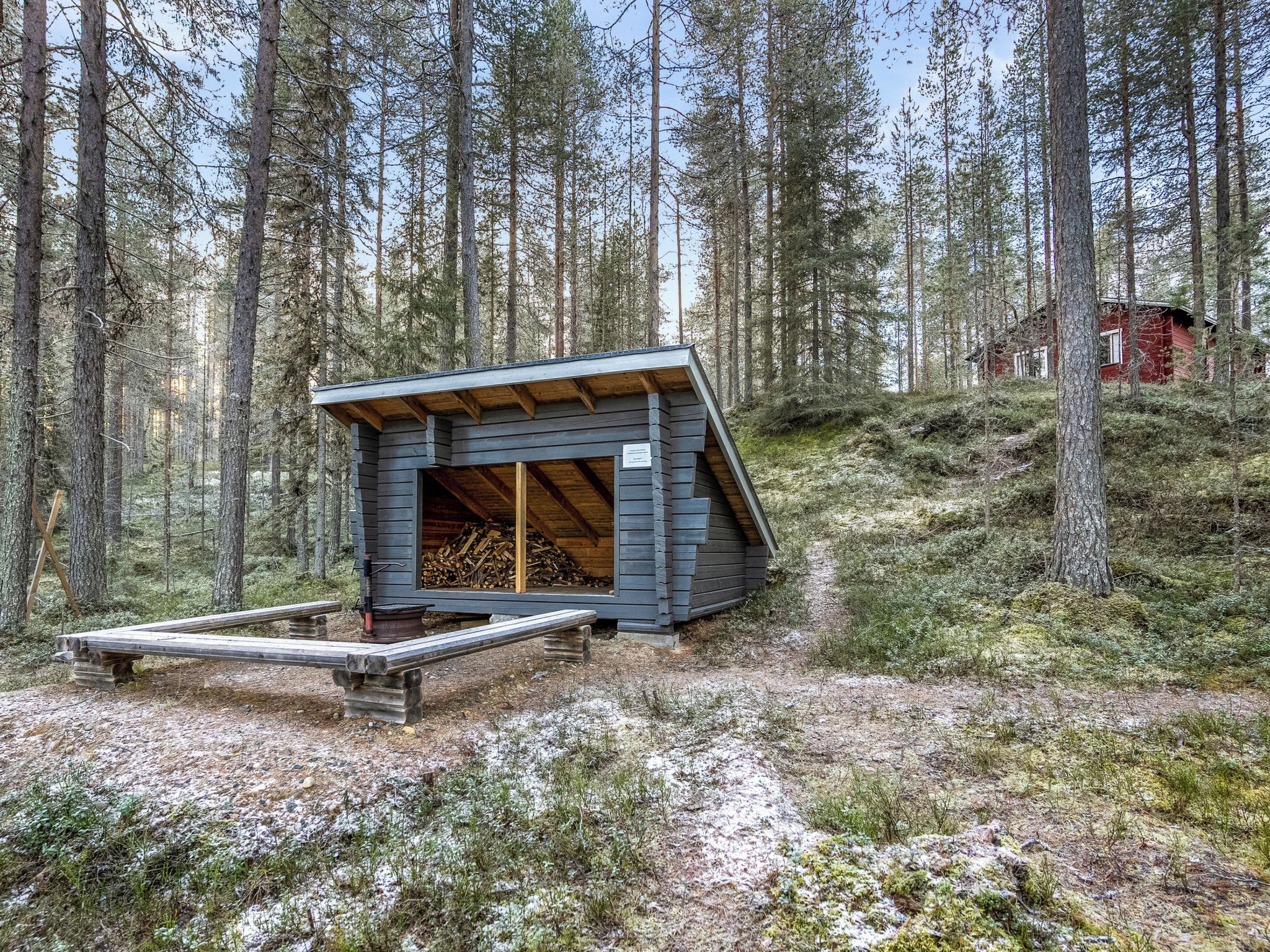 Una baita con tetto spiovente, un patio in legno e un braciere.