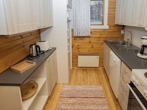 Una cocina funcional con armarios de madera, un tostador, una tetera, una cafetera y un lavamanos.