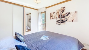 A bedroom with a large bed, a mirror, and abstract wall art.