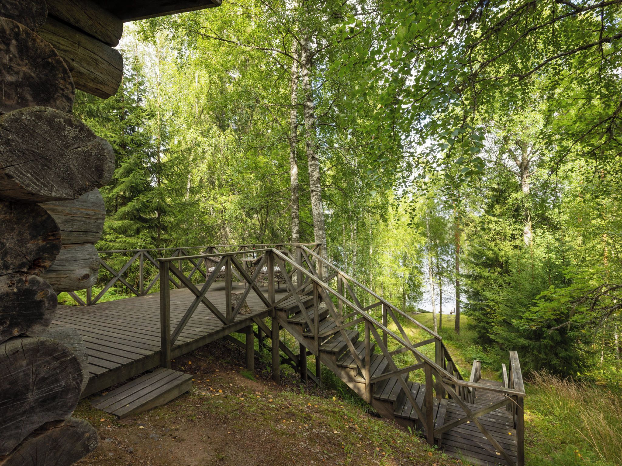 Una escalera de madera que lleva a una cabaña rodeada de un bosque frondoso.