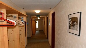 Un couloir avec des casiers en bois, un tableau encadré au mur et une porte au fond.