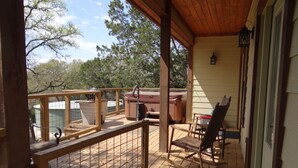 A wooden deck with a covered seating area, a hot tub, and a fenced-in section with a grill. - Home On The Range Charming Home - large private deck w/hot tub and Great Views (Wimberley)