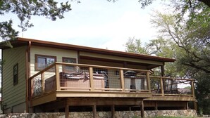 A two-story house with a wooden deck and stone foundation. - Home On The Range Charming Home - large private deck w/hot tub and Great Views (Wimberley)