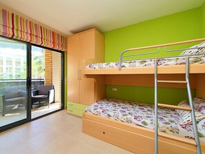 A bunk bed room with a sliding glass door leading to a balcony, a green wall, and a wooden cabinet. - Can Pavet by Interhome (Cambrils)