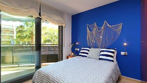 Une chambre avec un lit, un mur d’accent bleu, un balcon avec vue et une décoration murale.