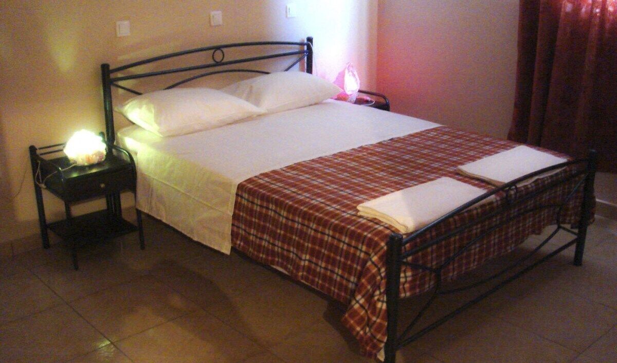 Een bed met een geruit dekbed, een bedlampje en een nachtkastje.