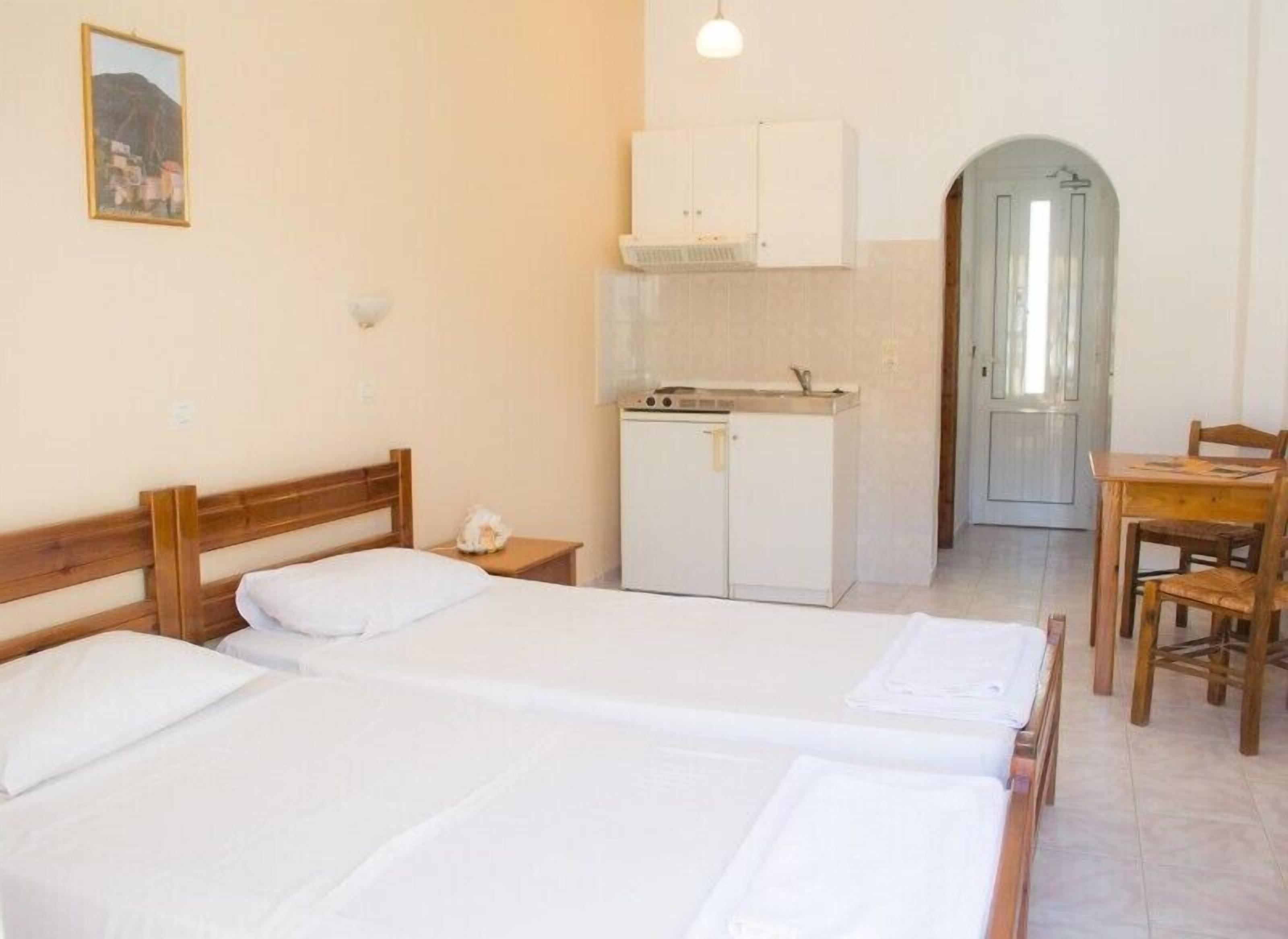 Een kamer met twee bedden, een kleine kitchenette en een eethoek.
