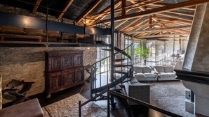 Un loft espacioso con vigas de madera a la vista, una escalera de caracol y una chimenea de piedra.
