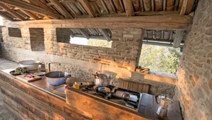 Una cocina rústica con paredes de piedra, techo de madera y estufa empotrada.
