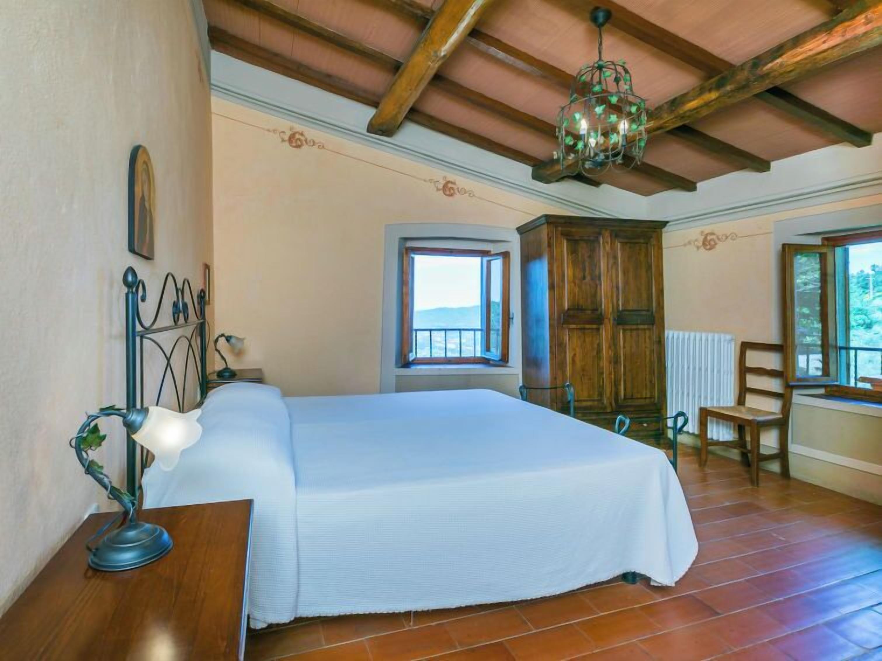 A bedroom with a bed, wooden wardrobe, and a window with a view.