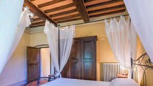 A bedroom with a bed, wooden ceiling beams, a radiator, and a window. - La Torre by Interhome (Reggello)