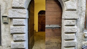 Un arco in pietra conduce a una porta di legno con un chiavistello metallico.