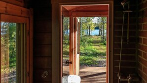 A wooden cabin with a door leading to a wooden deck overlooking a lake. - Niemenkärki, vaikon loma 8 by Interhome (Kaavi)