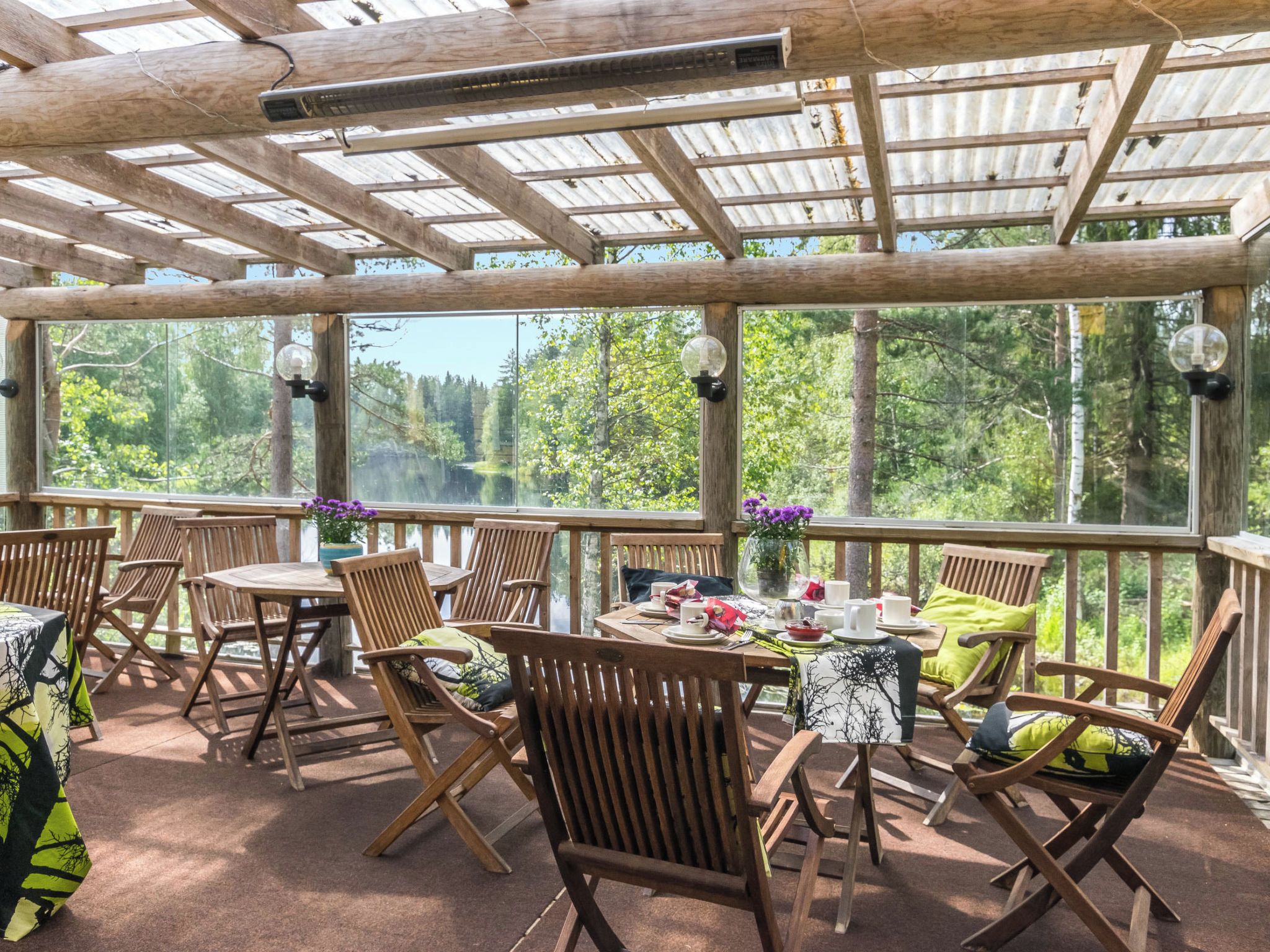 A covered outdoor seating area with wooden furniture and a table set for dining.