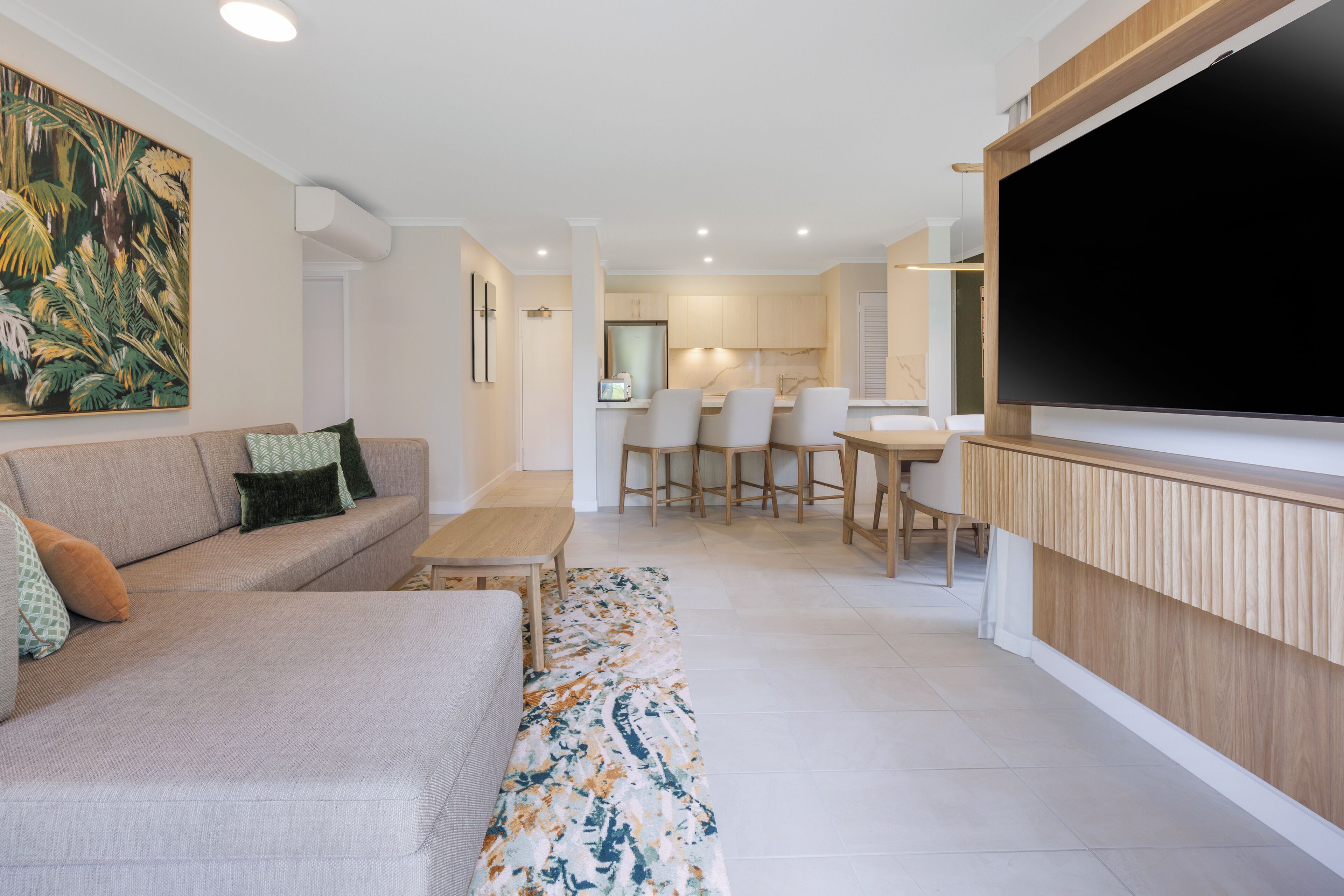 A modern living room with a sofa, a coffee table, and a TV mounted on the wall.