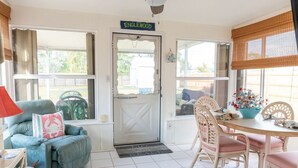 A cozy living area with a teal sofa, a dining table with pink chairs, and a white door labeled "Englewood". - Great location! Private fenced backyard. March/April 2027 available (Englewood)