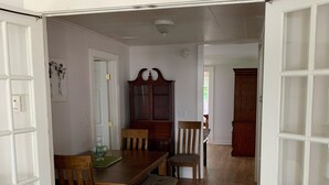 A dining area with a wooden table and chairs, a cabinet, and a door leading to another room.